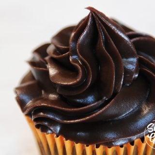 close up of chocolate ganache frosting piped onto a cupcake