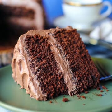 Slice of chocolate mayonnaise cake with chocolate buttercream on a green plate.