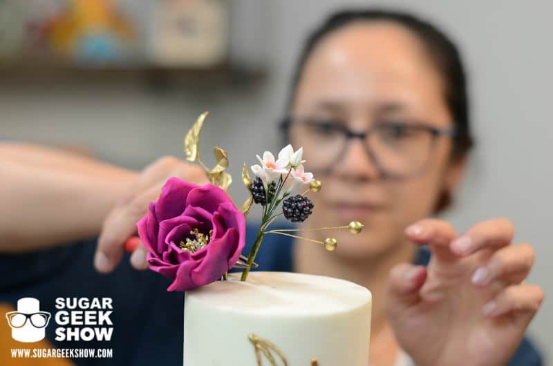 liz-marek-placing-flowers-in-cake-jewel-toned-mexican-inspired-wedding-cake