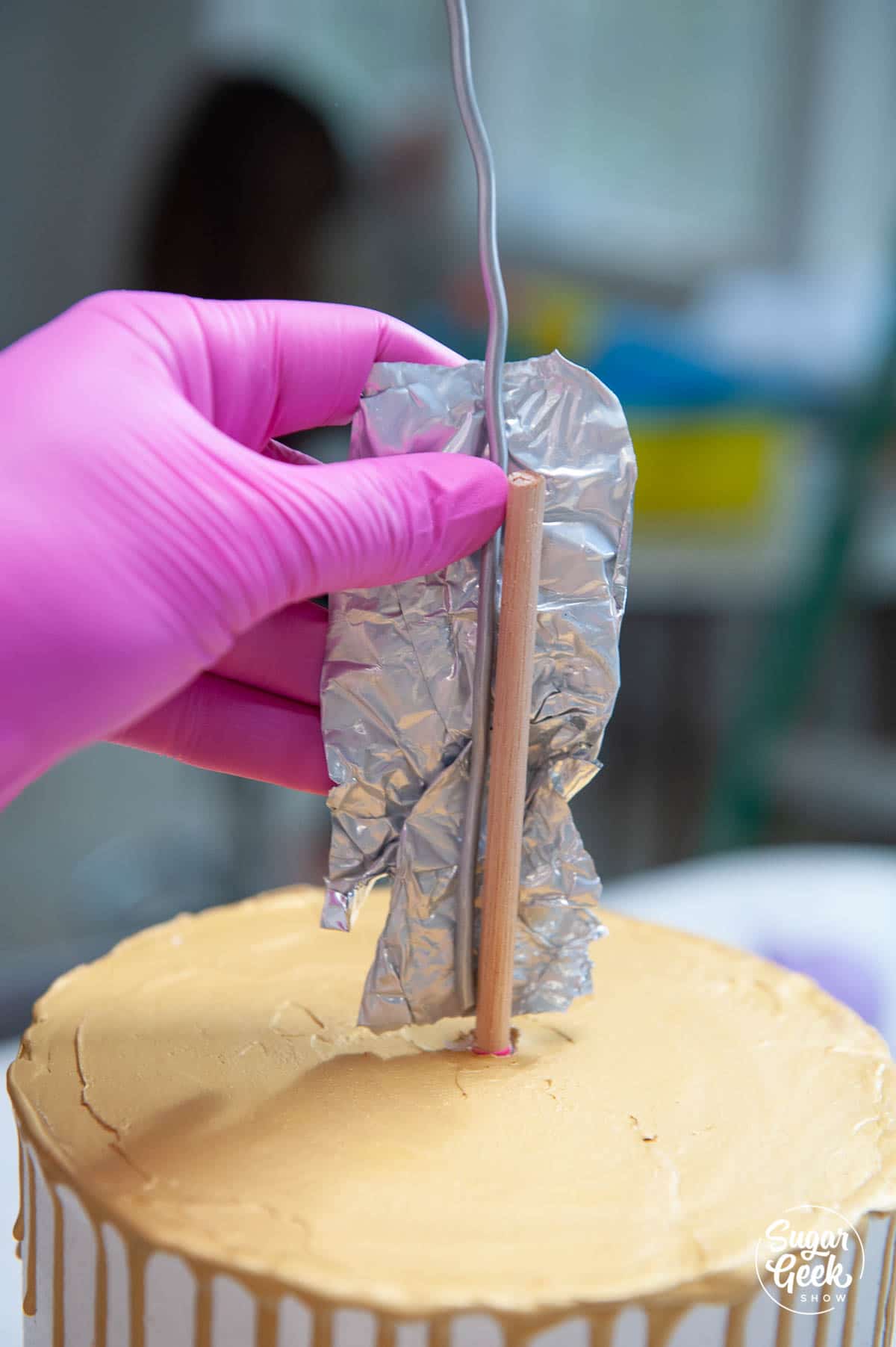 dowel inserted into the cake with aluminum foil tape