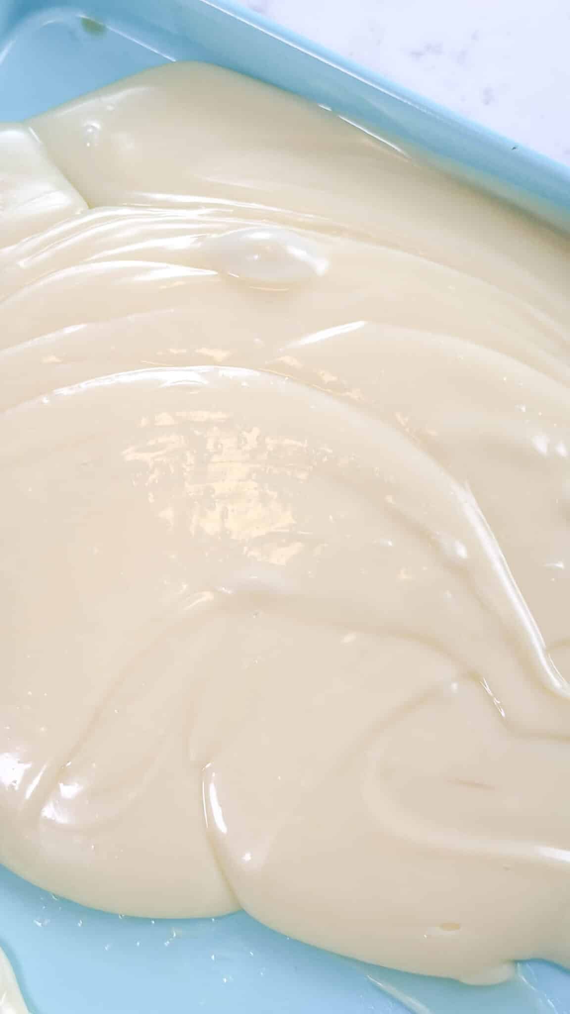 White chocolate ganache on a blue sheet pan.