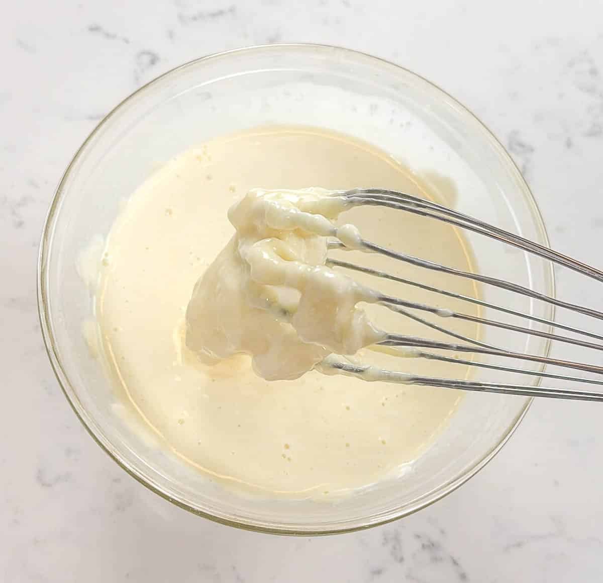 Whisk above a bowl of melted white chocolate ganache.
