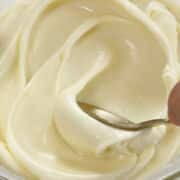 Gold spoon spreading out white chocolate ganache.