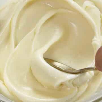 Gold spoon spreading out white chocolate ganache.