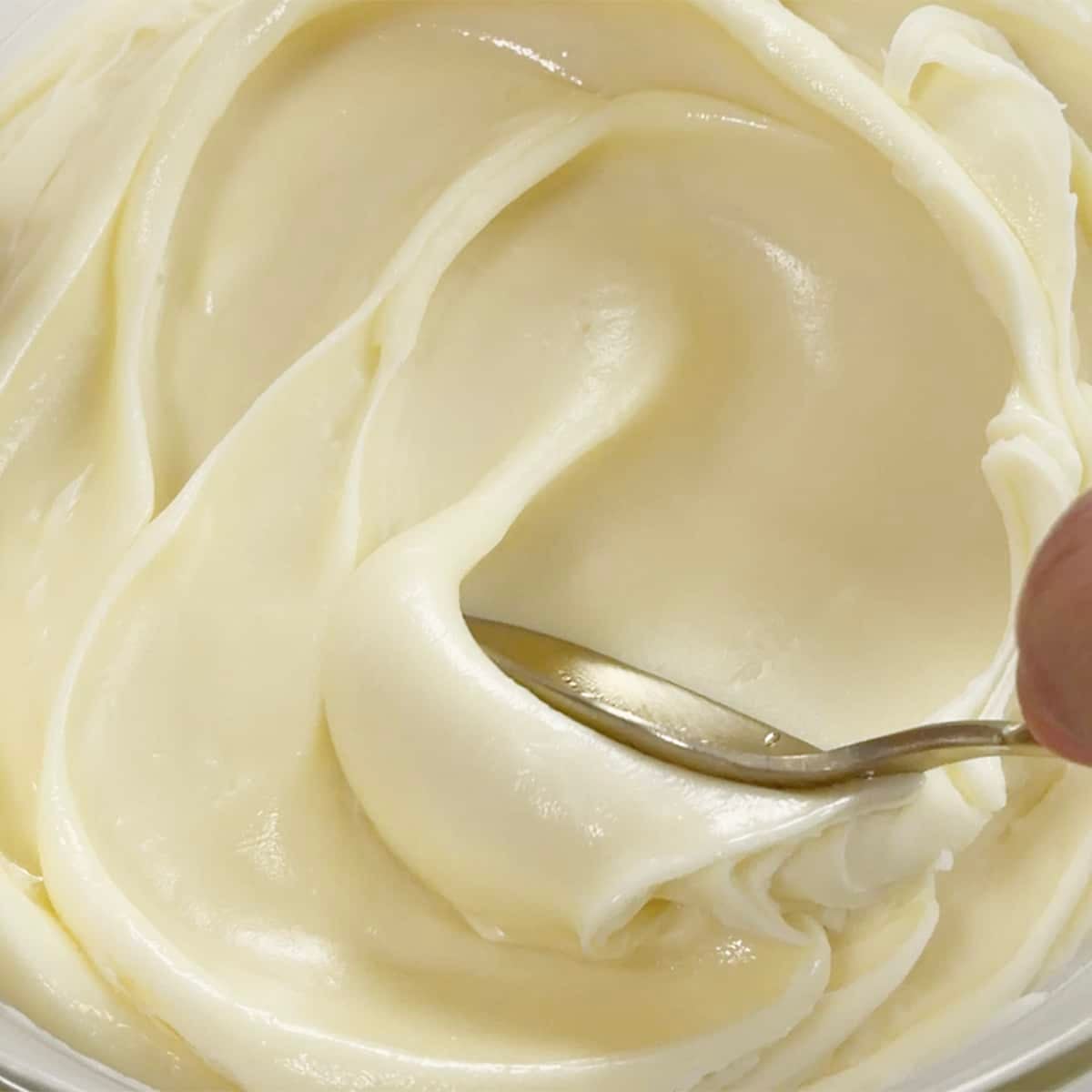 Gold spoon smoothing out white chocolate ganache.