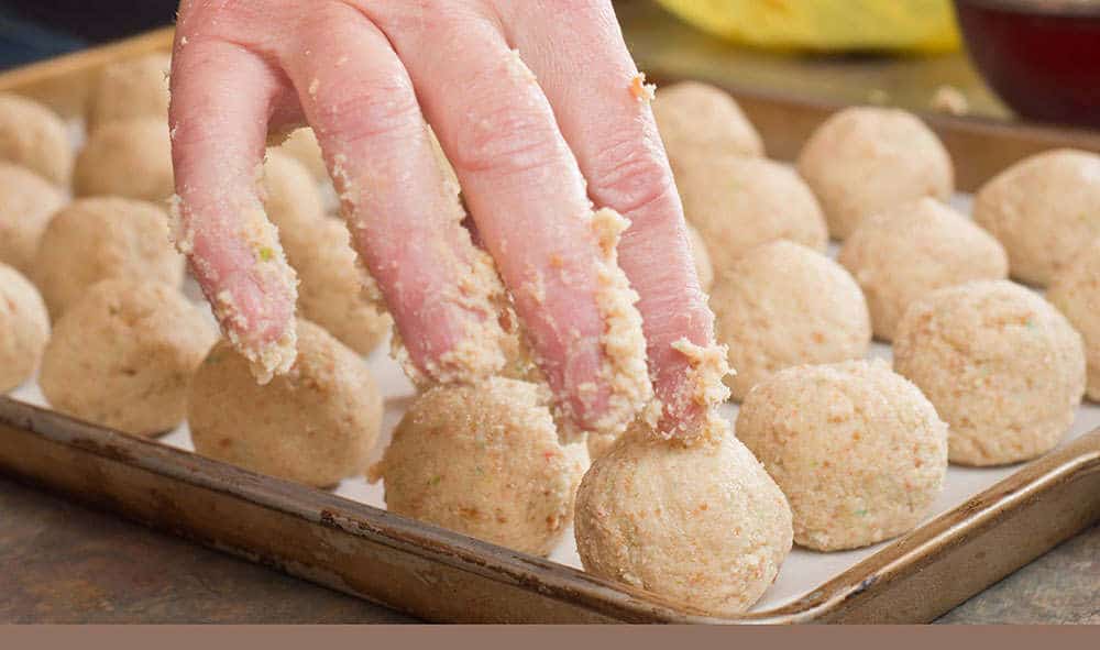 cake pop dough rolled into a ball and being placed onto a baking sheet