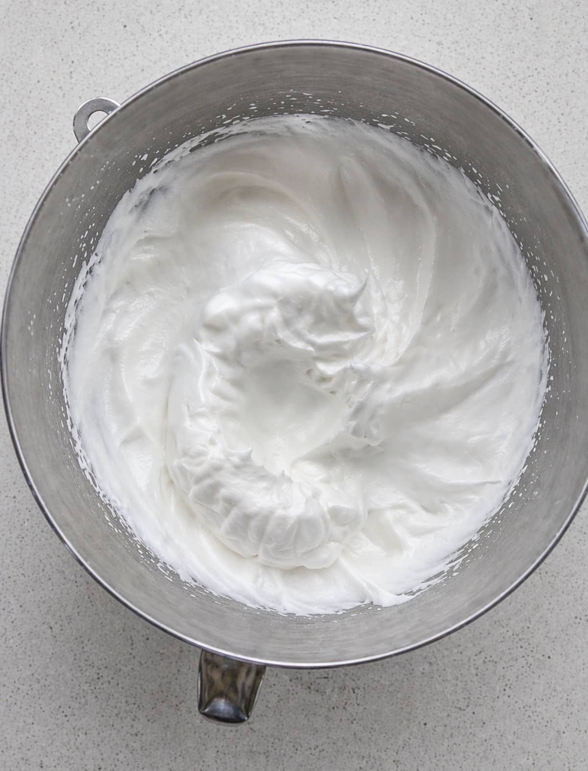 Whipped meringue in a metal mixing bowl.