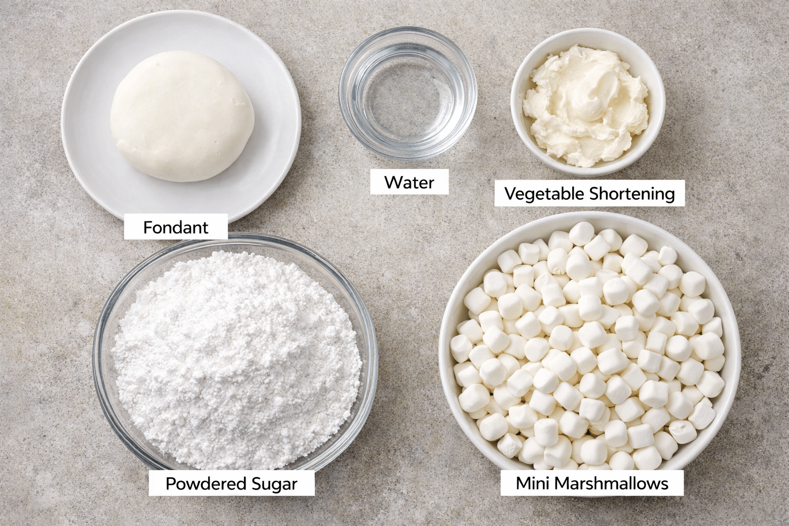 Homemade fondant ingredients in bowls on a grey countertop.