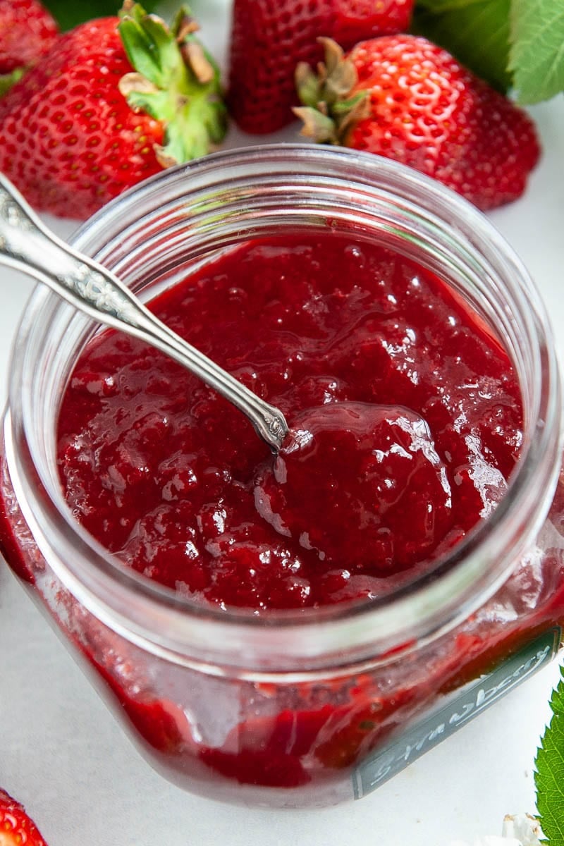 Close up of strawberry reduction in a container with a spoon.
