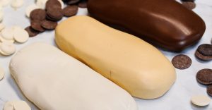white, ivory, and dark brown modeling chocolate surround by chocolate chips on a white countertop