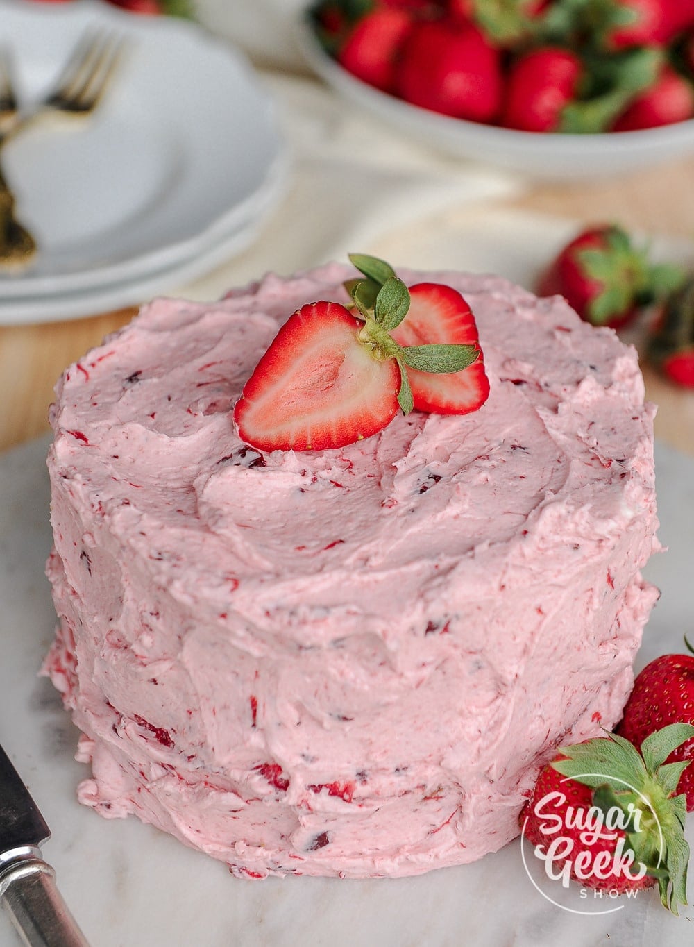 Strawberry cake with fresh strawberries on top on a marble cake board.
