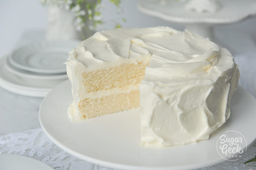 Frosted white cake on a white platter.