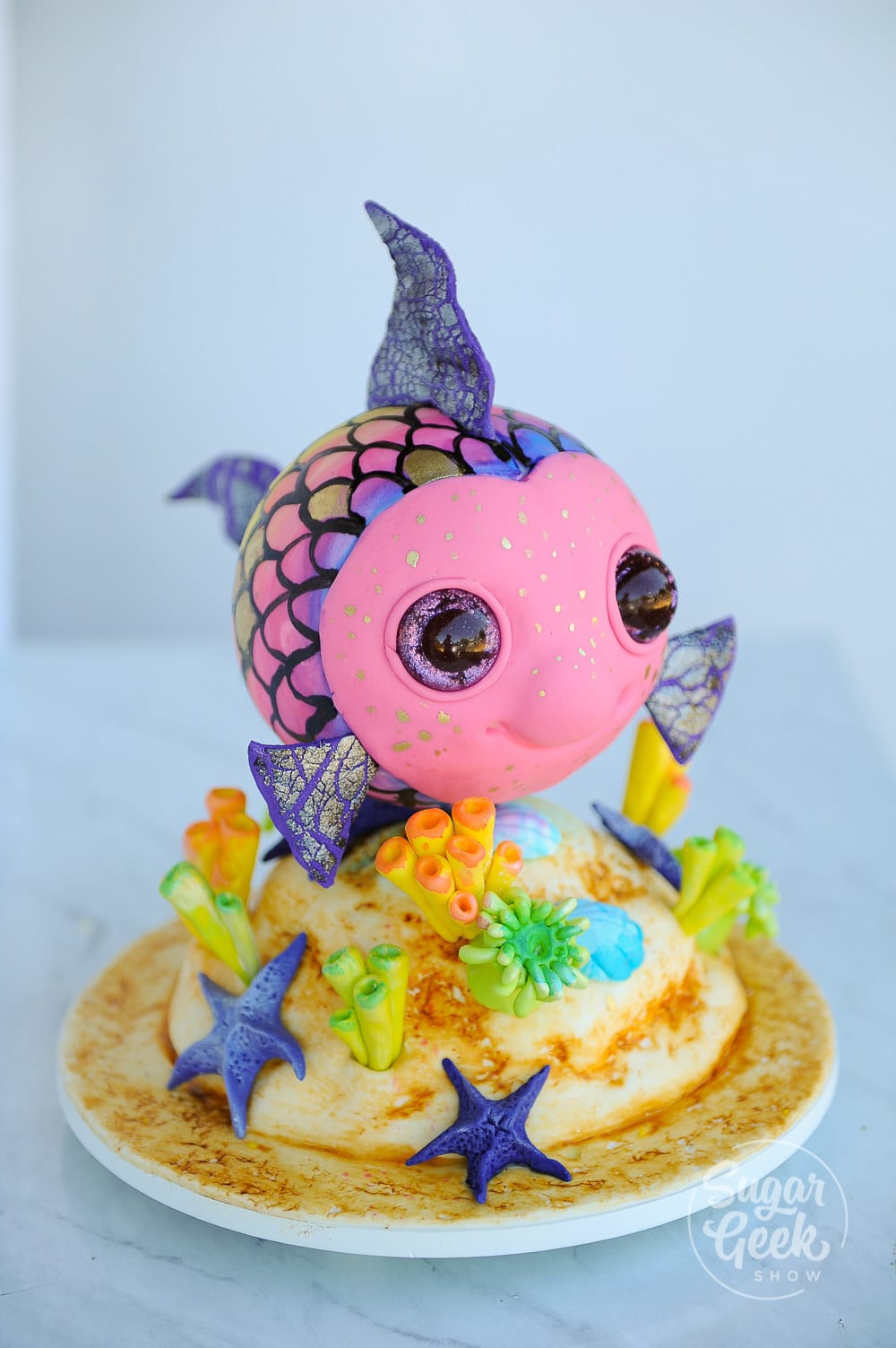 rainbow fish tutorial with a simple cake structure, glitter eyes, crackled fondant and fun watercolor scales