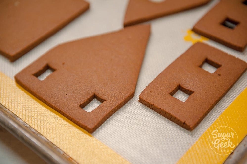 Gingerbread house pieces placed on a silicone baking mat ready to bake in the oven. 