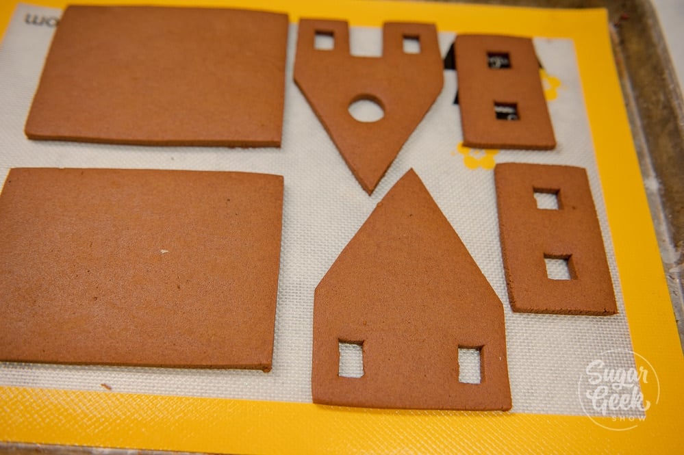 Baked gingerbread house pieces on a silicone baking mat. 