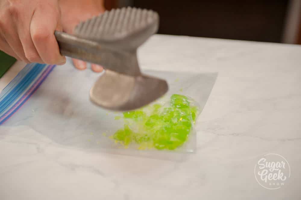 Mallet crushing jolly rancher candy in a ziplock bag