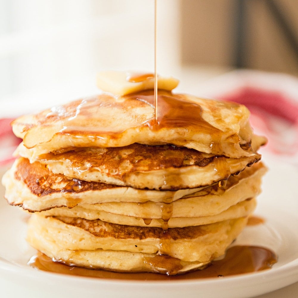 stack of brown butter buttermilk pancakes with syrup being drizzled on top