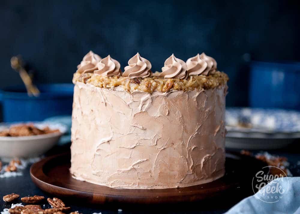 close up of german chocolate cake frosted with chocolate swiss meringue buttercream and coconut pecan frosting