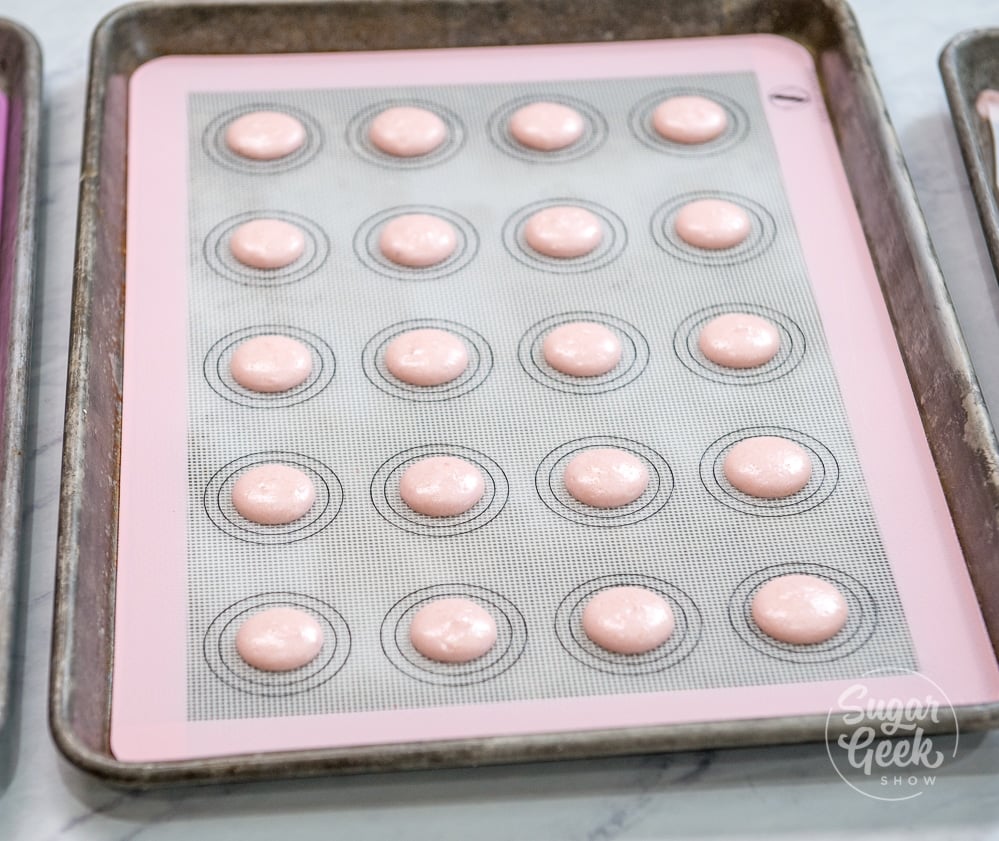 strawberry macarons drying on a silicone mat