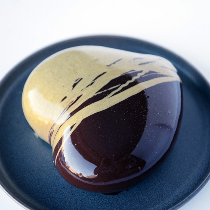 chocolate mirror glaze cake with gold drizzle on a black plate