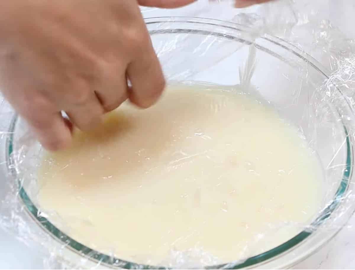 Ermine frosting roux in a clear bowl with plastic wrap on top.