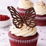 close up of a chocolate butterfly decoration on a red velvet cupcake