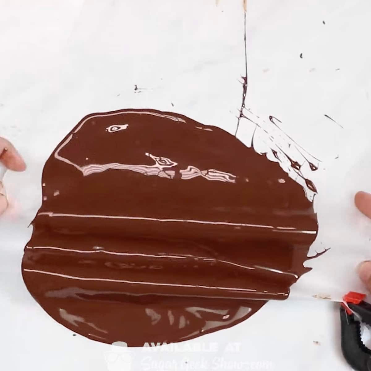 tempered chocolate being gathered on parchment paper