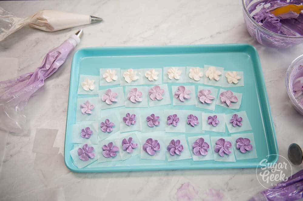 purple and white buttercream flowers on a cake