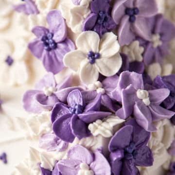 Pastel colored buttercream flowers on a white cake.