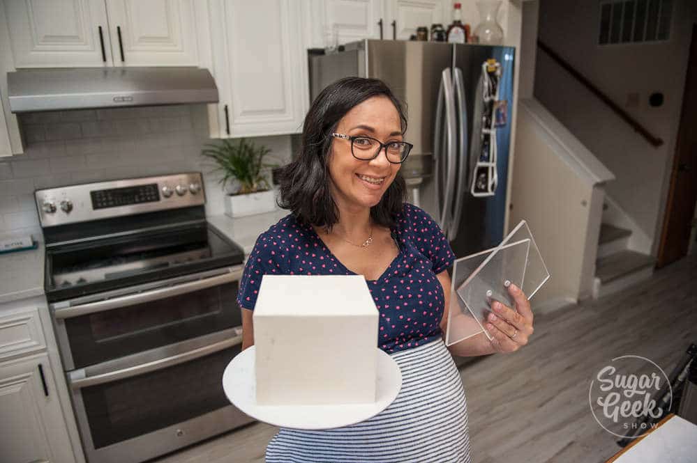 liz marek holding a square buttercream cake and square acrylics in the other hand