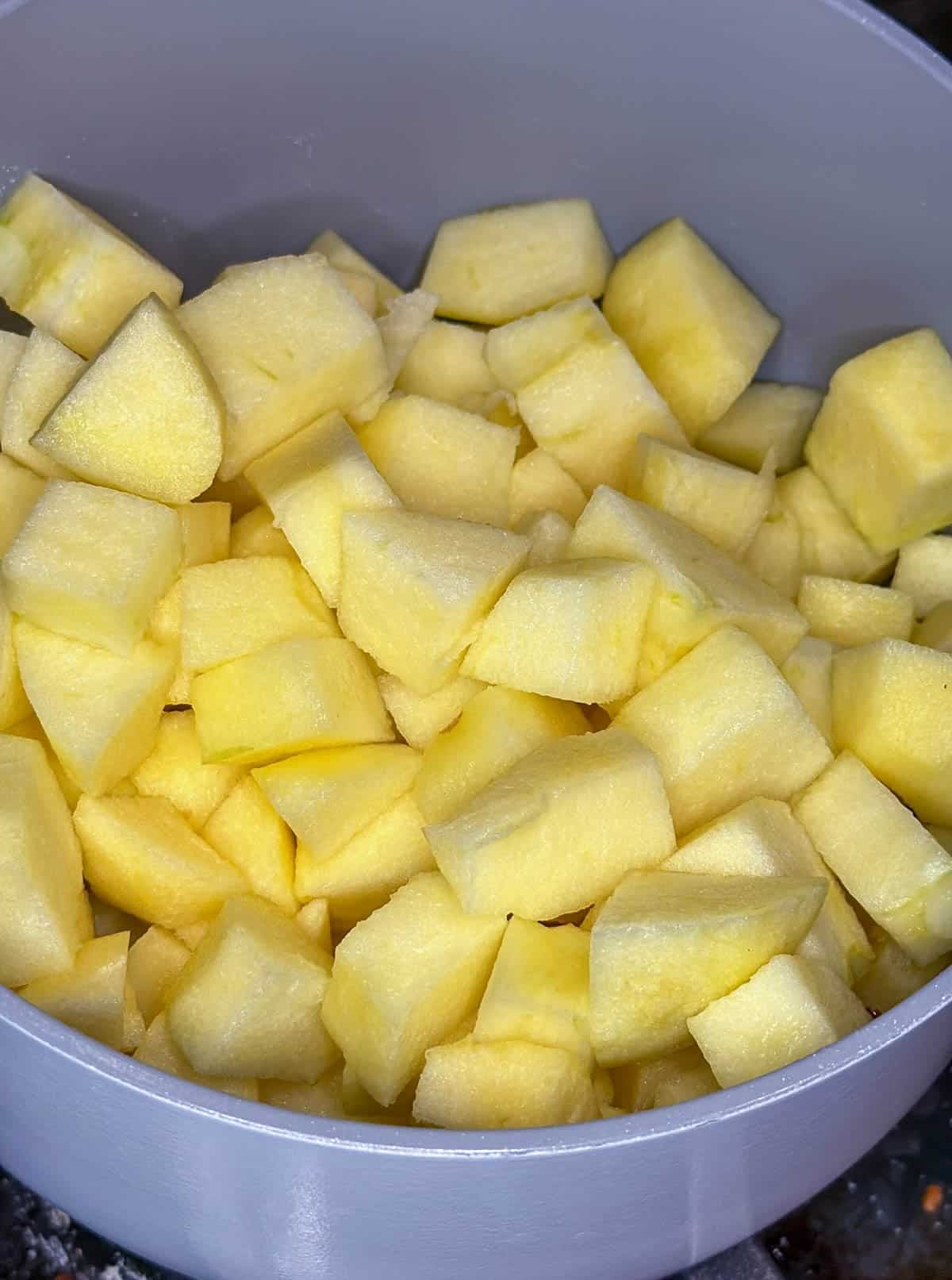 Cubed apples in a white and grey saucepan.