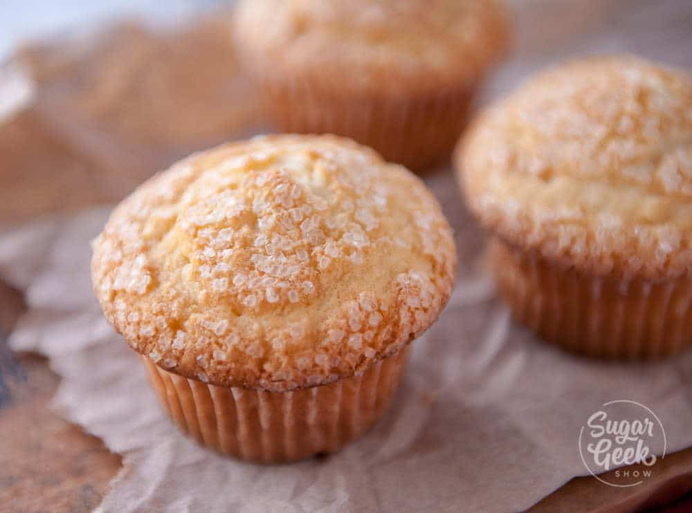 three basic muffins with sparkling sugar on top of brown paper