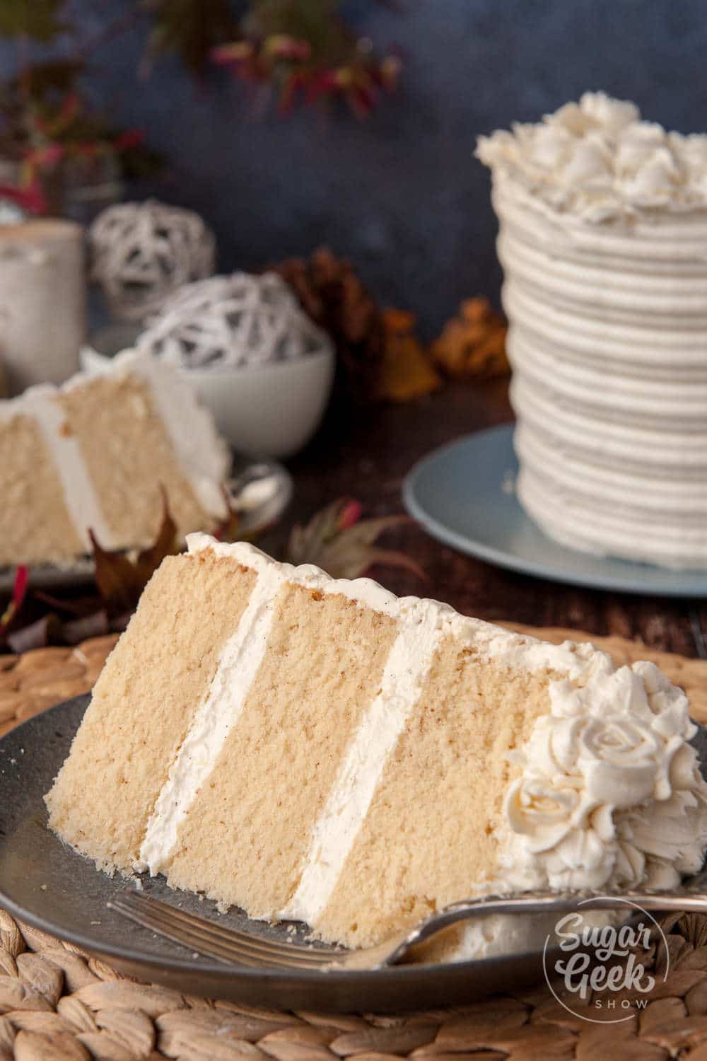 brown butter cake with vanilla bean buttercream on a plate with cake and second slice in the background