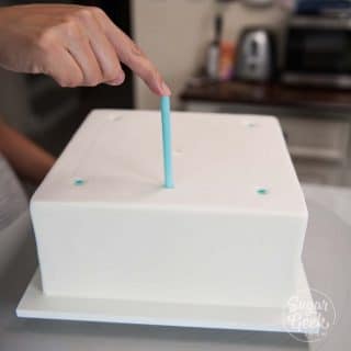 inserting thick milkshake straws into a chilled cake using the straw guide
