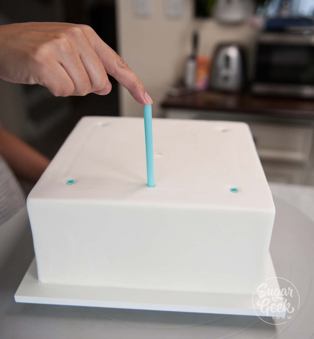 inserting thick milkshake straws into a chilled cake using the straw guide