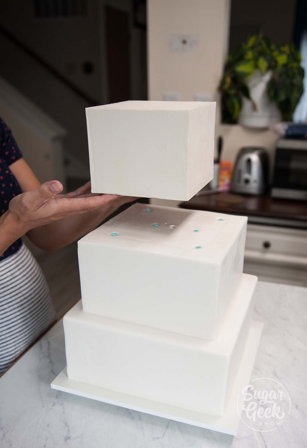 stacking a square wedding cake with milkshake straws