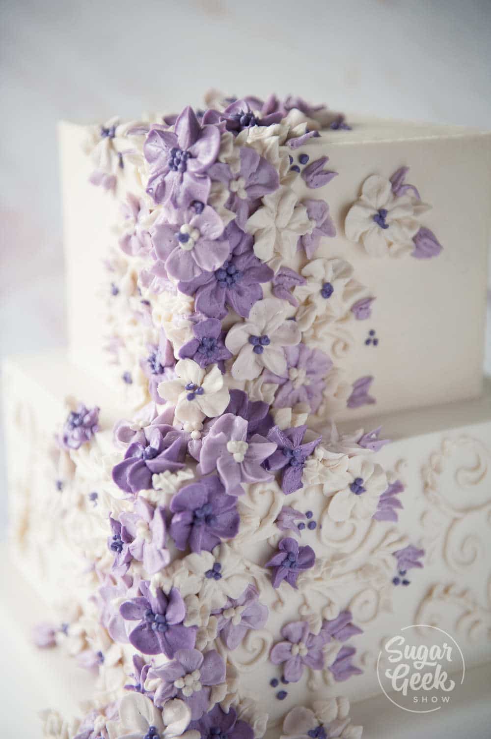 Purple buttercream flowers on a wedding cake