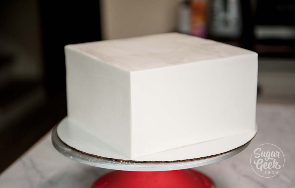 square wedding cake tier covered in fondant sitting on a turntable