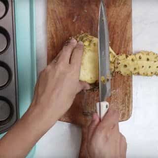 Trim off the outside skin of the pineapple with a sharp knife