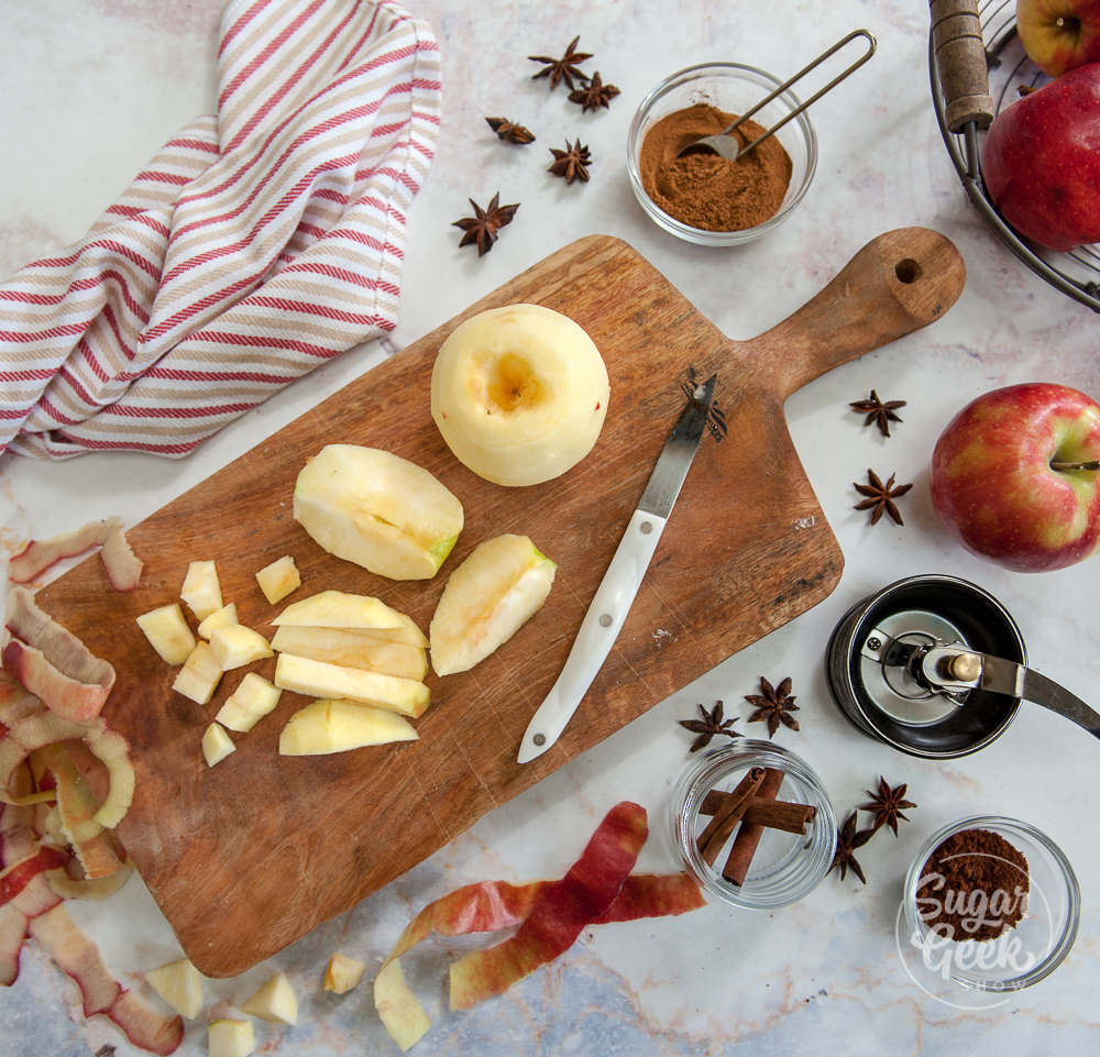 prepping apples to make apple filling. Cut up apples on wooden cutting board with knife surrounded by spices and apple peels