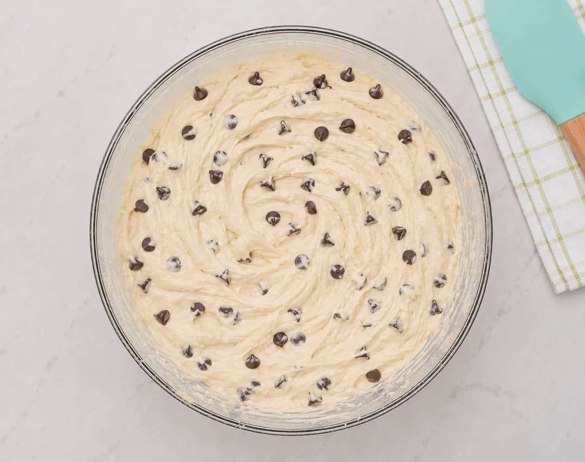 Muffin batter with chocolate chips in a glass mixing bowl.