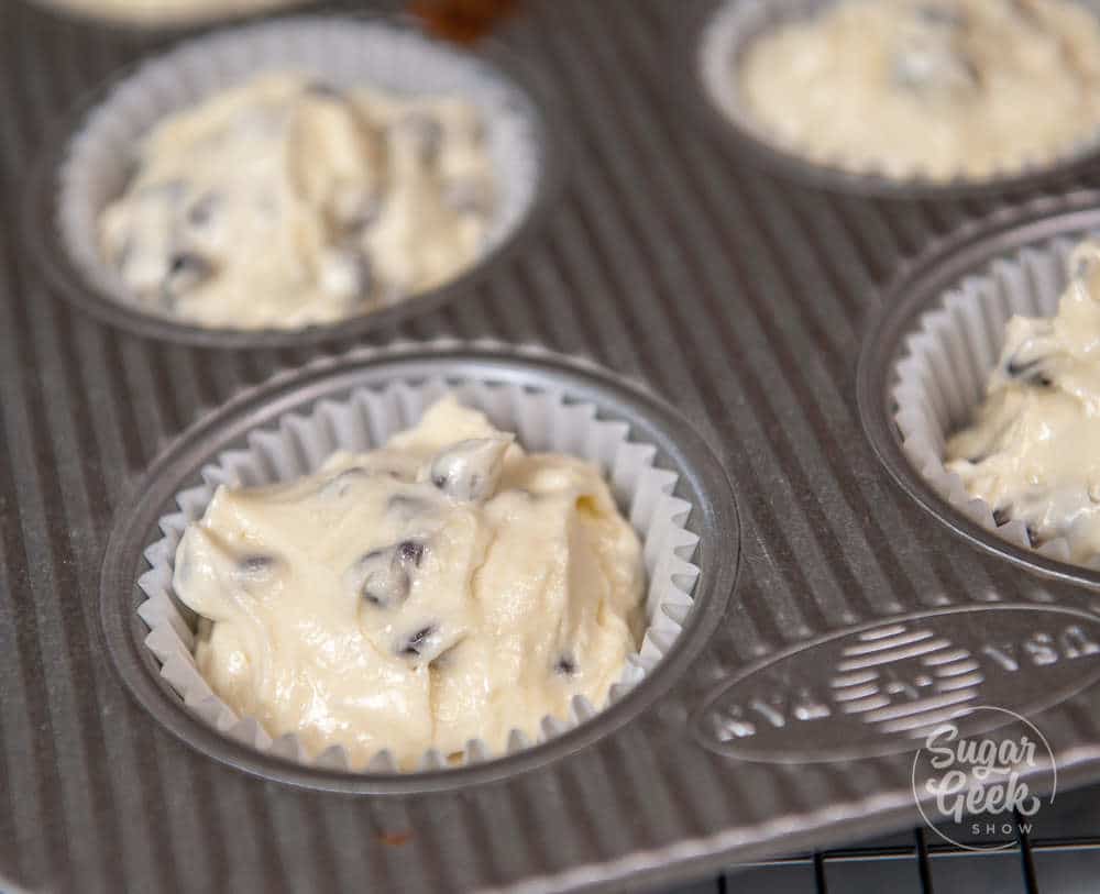 chocolate chip muffin batter in muffin tin with muffin liners, filled all the way to the top