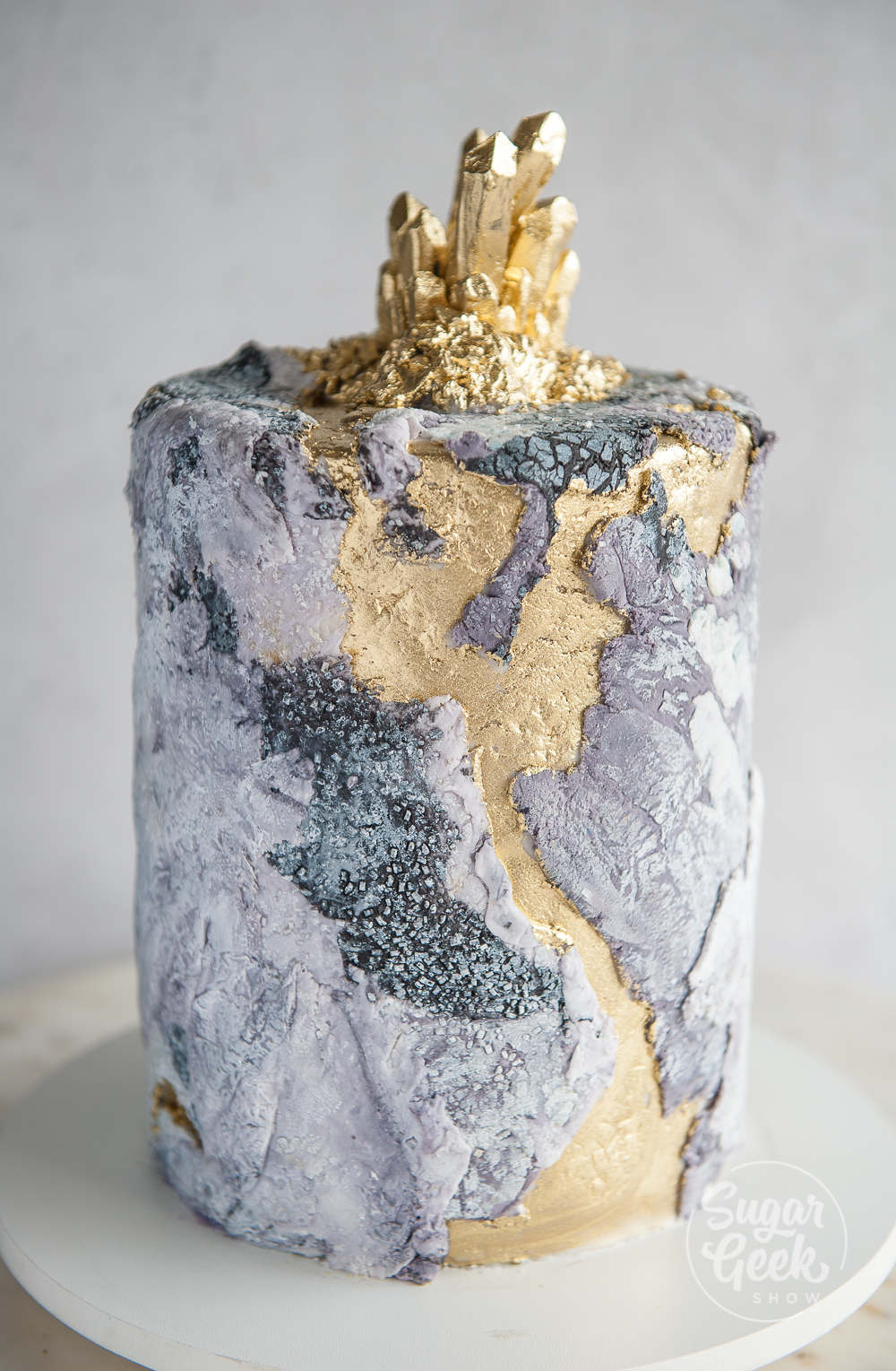 gold painted on buttercream in between fondant pieces on a stone texture cake