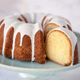 close up of vanilla bundt cake with vanilla glaze and slice cut out of the cake