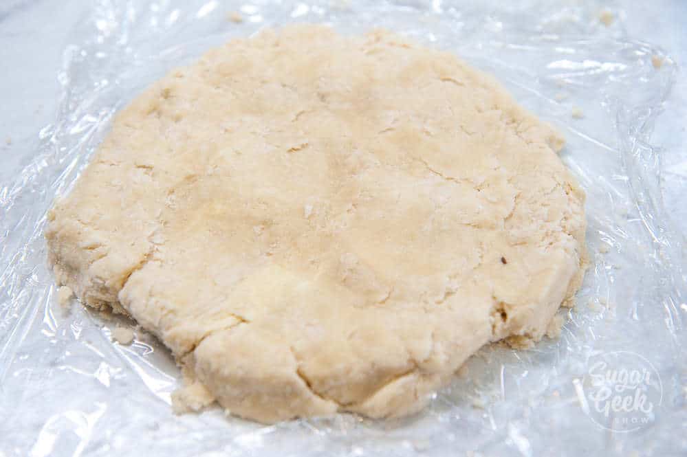 close up of mealy pie dough on plastic wrap