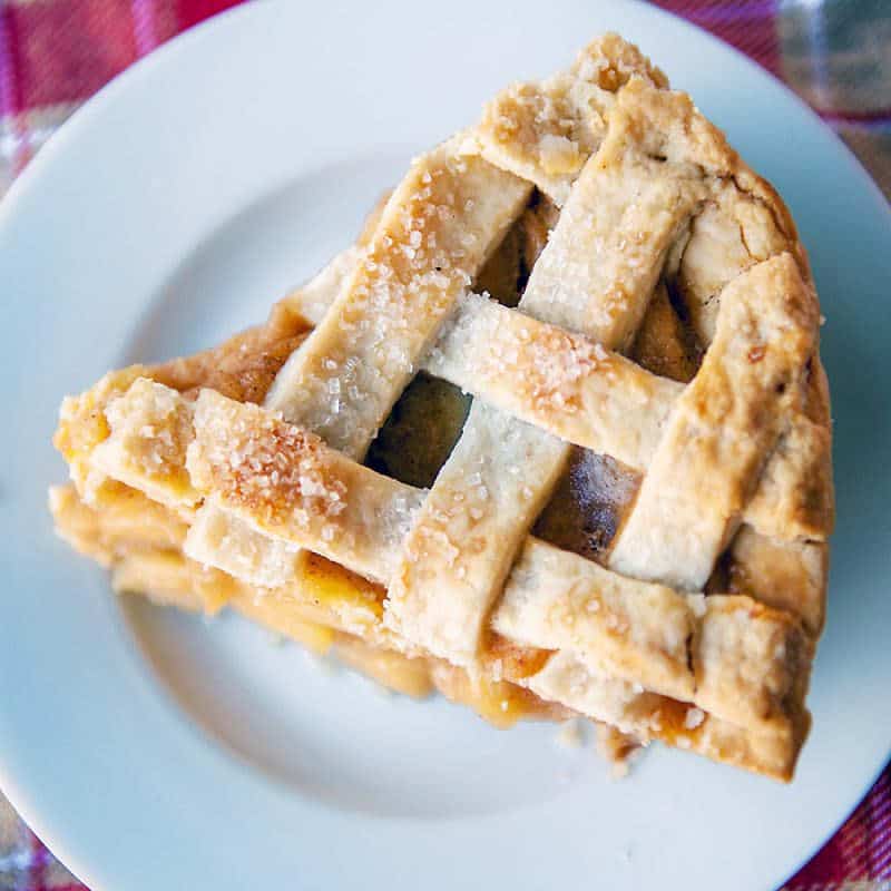 close up of a slice of pie with lattice crust top on a white plate
