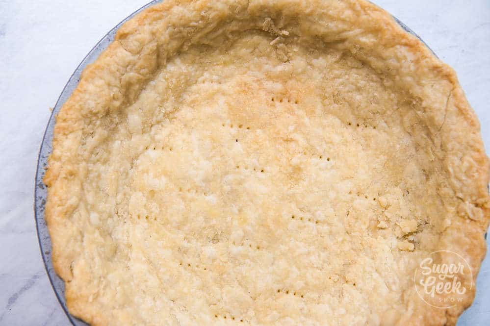 closeup of flakey pie dough in a pie pan that has been blind baked