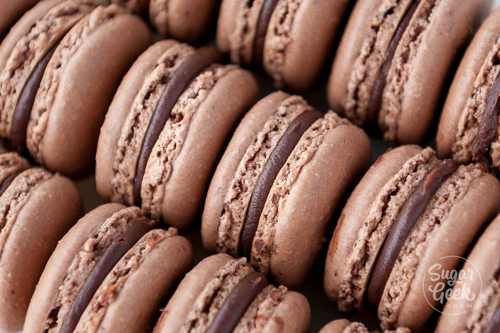Rows of chocolate macarons filled with chocolate ganache.
