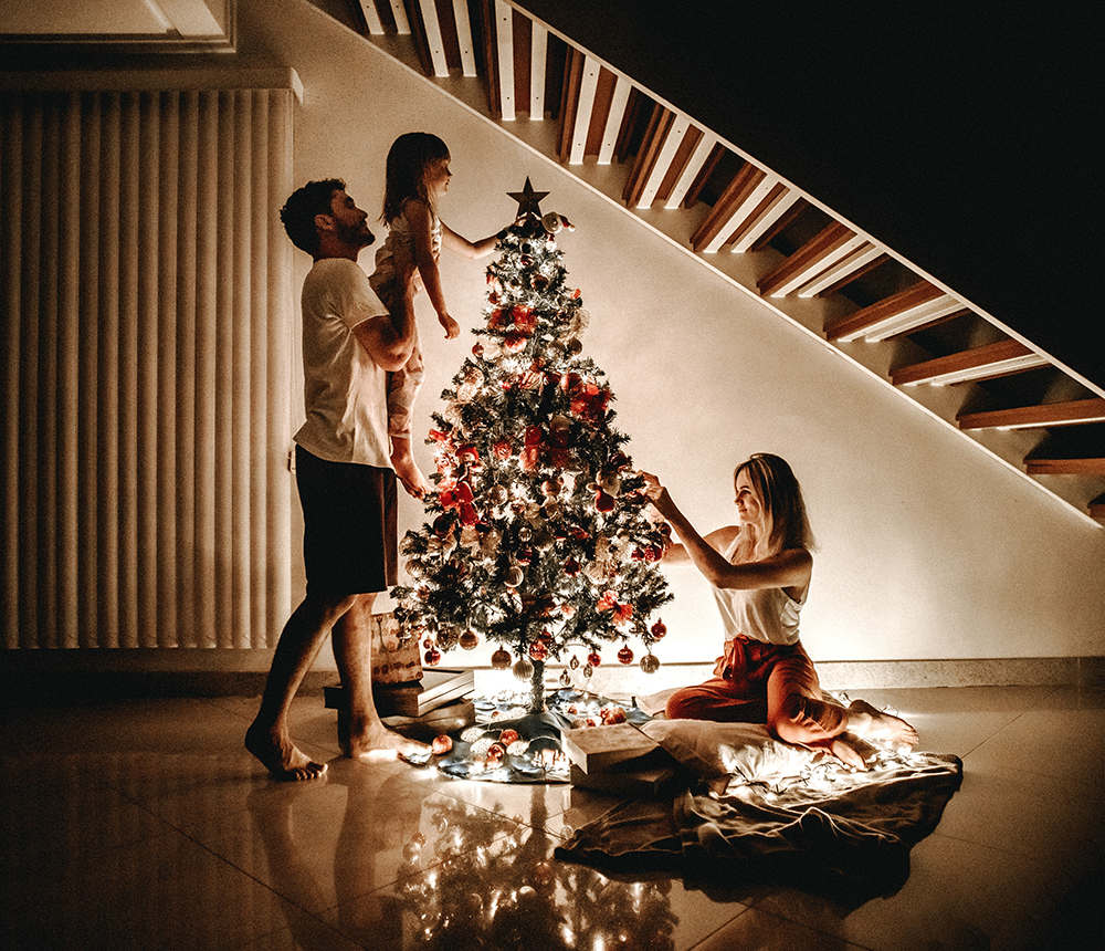 family decorating a christmas tree in dimly lit room
