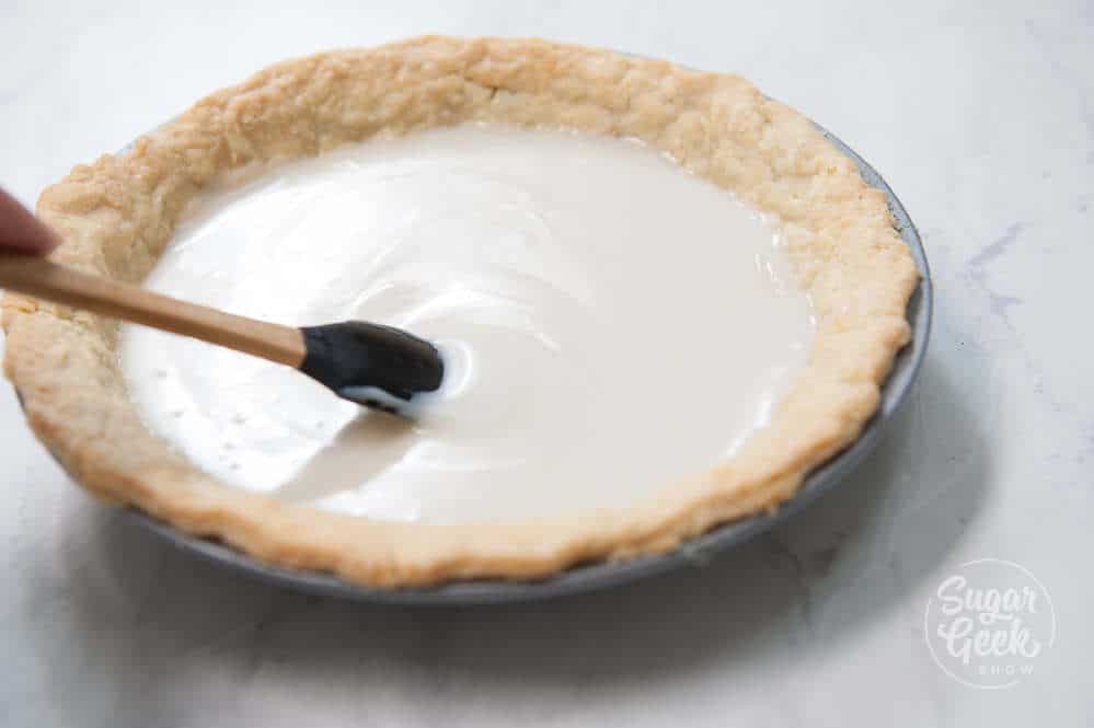 pie dough with pie filling added and a spatula smoothing down the filling